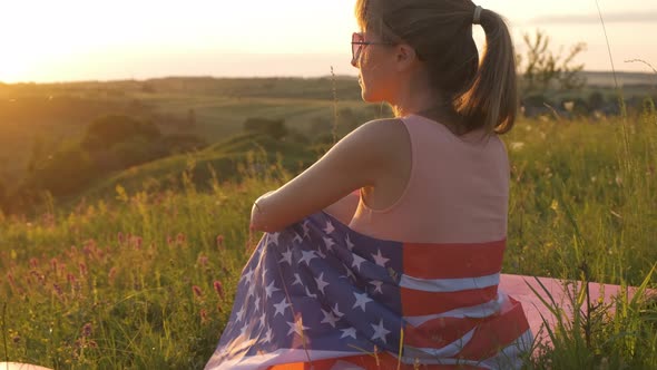 Happy woman with USA national flag outdoors at sunset. Positive girl celebrating United States  alt