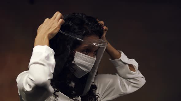 Medical professional with a face mask and shield adjusts the headgear for best protection against a alt