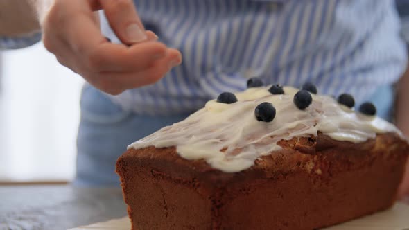 Close Up of Woman Decorating Cake with Blueberries