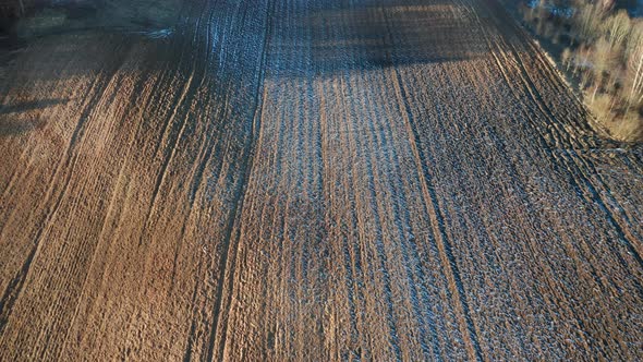 AERIAL: Sun Casts Shadows on Ploughed Frozen Farm Land
