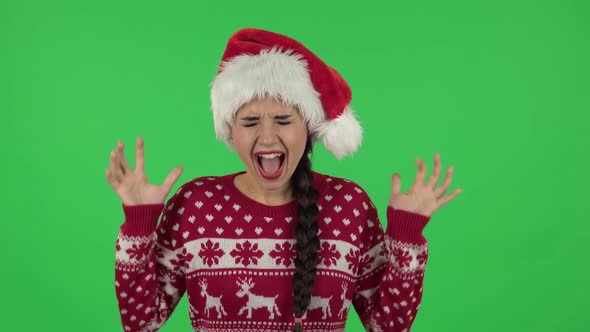 Portrait of Sweety Girl in Santa Claus Hat Is Screaming. Green Screen alt
