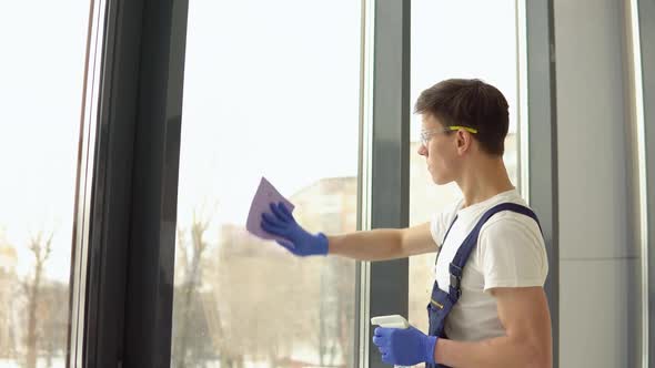 Young Serviceman in Protective Uniform and Glasses Washes Windows alt
