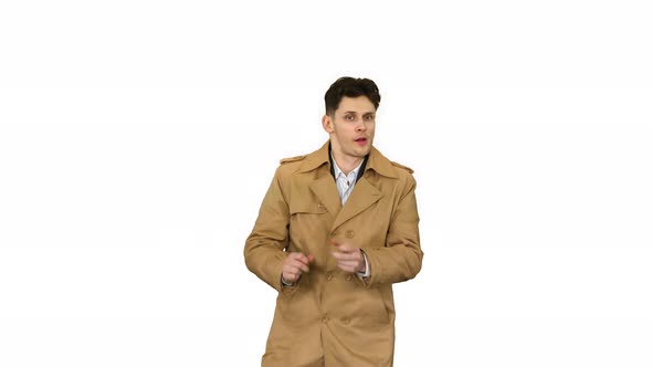 Young Man Wearing Trench Coat Dancing and Having Fun on White Background. alt