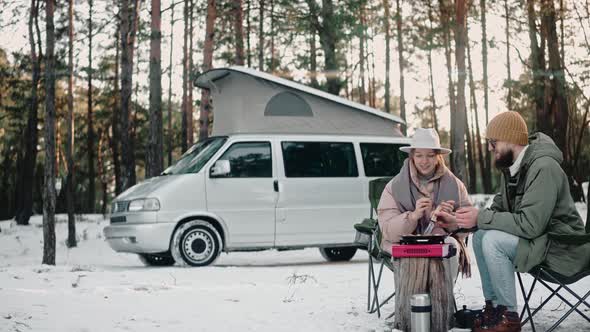 Couple Cooking Lunch at the Camp in the Woods on a Winter Day Enjoying Van Life