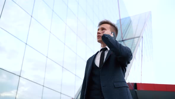 Businessman Talking on Phone Against the Building with a Glass Facade alt