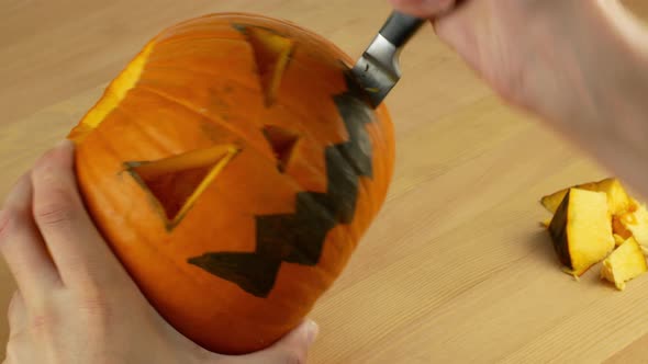 A man cleans and carves the eyes and mouth of a pumpkin in preparation for Halloween.