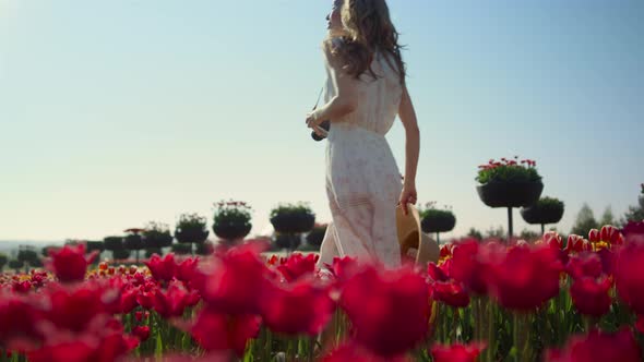 Beautiful Girl with Camera Walking Through Tulip Field alt