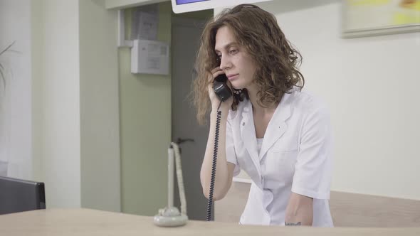 Receptionist Receiving Call in Hospital. Portrait of Concentrated Caucasian Woman Consulting Patient alt