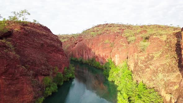 Drone flying through straight through a gorge/canyon with large red rock walls on either side and a alt