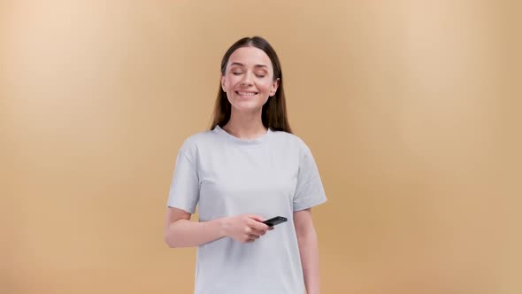 Attractive Cheerful Girl Switching Channel Having Fun with a Delighted Smile Isolated Over Beige alt