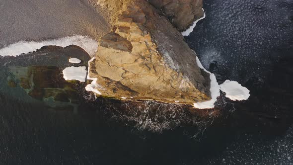 Waves Hit the Coastal Rock Which is Surrounded By Ice Frozen on It alt