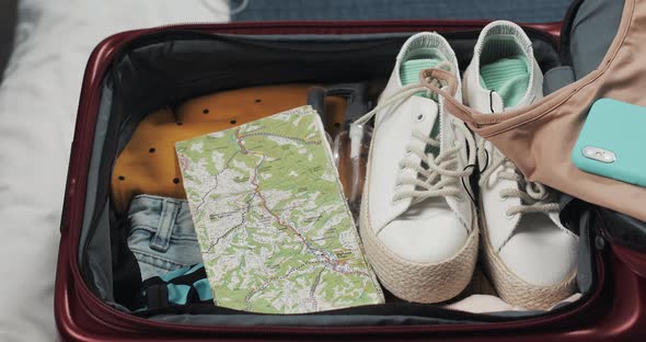 Woman's Hands Packing Suitcase for a Journey on the Bed at Home. Travel Preparations alt