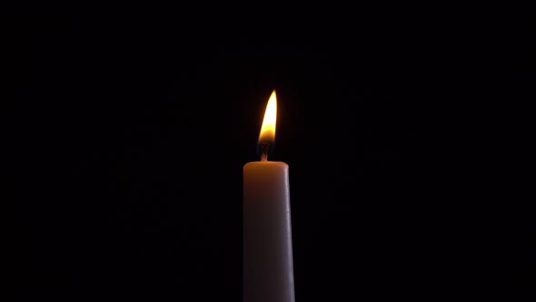 view of a burning candle on a black background
