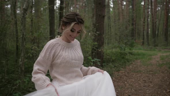 A Young Cheerful and Joyful Bride in a Wedding Dress and a Delicate Sweater Runs and Spins alt