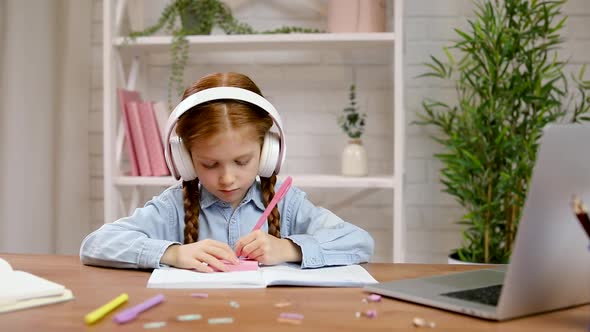 Little Child Girl Using Laptop for Doing School Tasks at Home and Writing Notes.