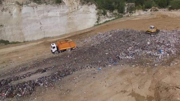 A truck unloading garbage to junkyard. Aerial shot. alt