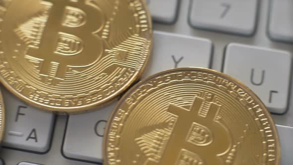 Golden Bitcoins on a White Keyboard Background