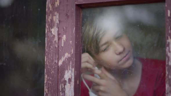 Boy in Mask Inside Looks at the Window Takes Off the Mask and Enjoy alt