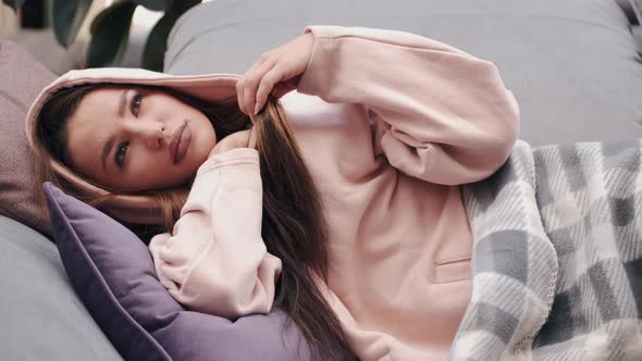 The Pretty Woman in Hoodie Is Placing the Thermometer in an Armpit Lying in Bed alt