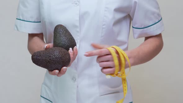 Nutritionist Doctor Healthy Lifestyle Concept - Holding Organic Avocado Fruit and Measuring Tape alt
