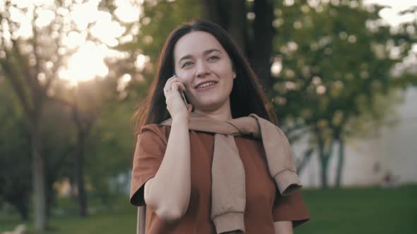 Happy smiling girl speaking phone . Cheerful girl talking using smartphone outdoors.