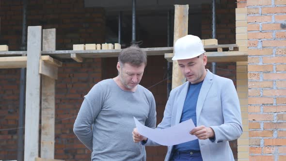 Engineer and Client Looking on Project on the Construction Site