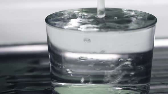 Glass filling to overflowing with clean drinking water until it overflows alt