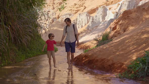 A Family Walks Along a Red Canyon or Fairy Stream at the Border of Desert in the Mui Ne Village in alt