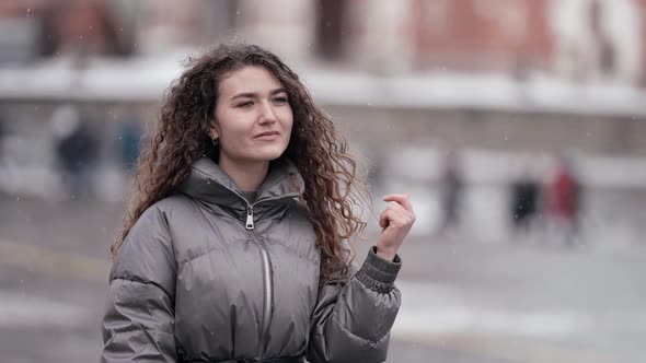 Carefree Young Woman is Walking in City at Winter Snow is Falling Portrait of Female City Dweller alt
