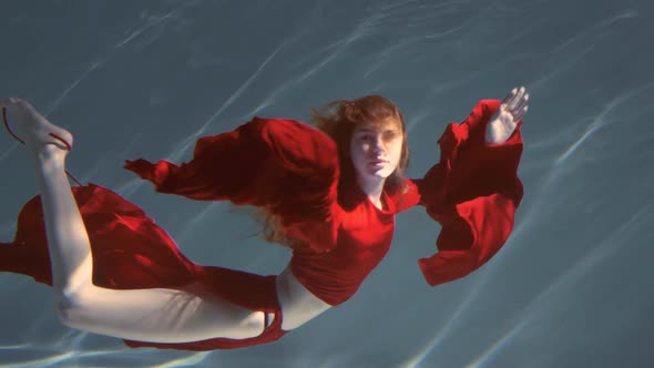 Attractive Redhaired Young Woman Swims Beautifully Underwater in a Red Dress alt