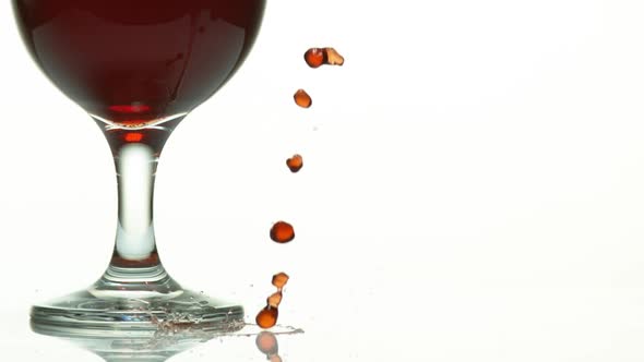 Red Wine being poured near Glass, against White Background, Slow motion