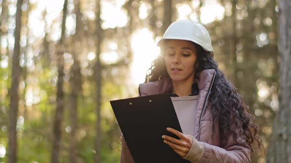 Millennial Experienced Female Technician with Clipboard Taking Measures for Reforestation of alt
