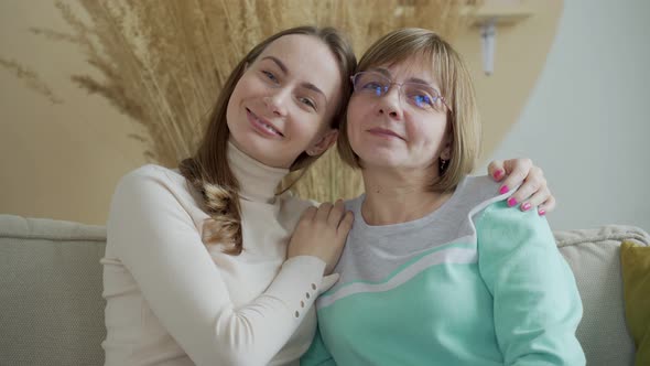 Horizontal Image of Cute Young Daughter in Stylish Hipster Eyeglasses Embracing Her Mother with Love alt