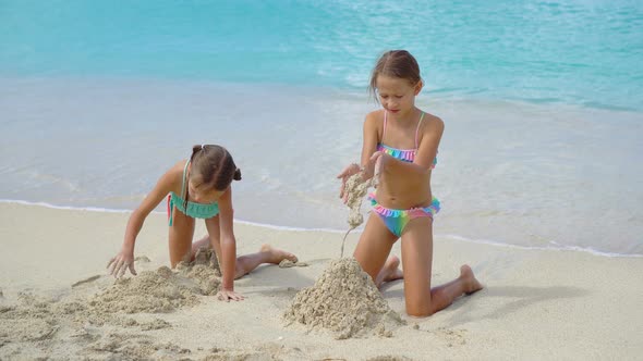 Two Little Happy Girls Have a Lot of Fun at Tropical Beach Playing Together at Shallow Water. Kids by travnikovstudio 