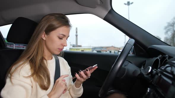 A Young Girl Reads a Message in the Phone She is in the Car alt