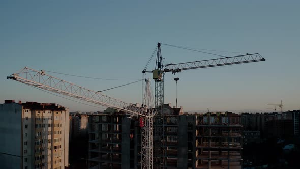 Aerial Drone View of Construction Cranes in Sunset Light. Construction Site Building in City alt