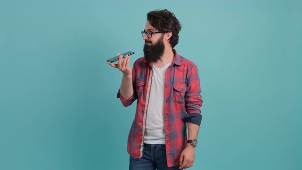 Bearded Man Holding His Smartphone Near His Mouth While Recording a Vocal Massage alt