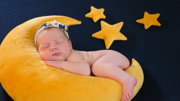 Little Infant As Model at Photo Shoot Sleeping and Posing on Yellow Soft Toy in Moon Shape and Stars alt