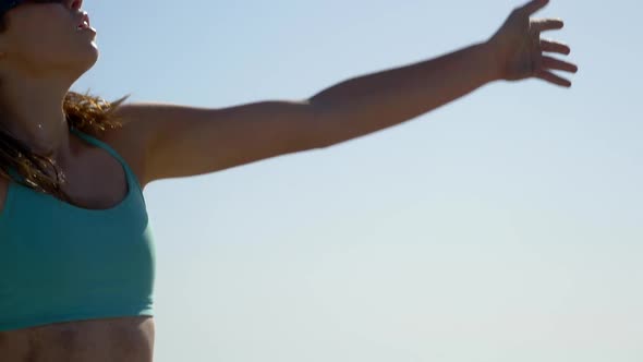 Women players play beach volleyball and a player serves the ball. alt