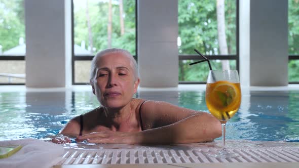 Mature Woman Swimming To Pool Side in Spa Hotel alt