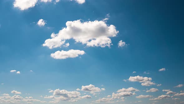 Timelapse White Fluffy Olakas Float Through the Blue Sky on a Sunny Day alt