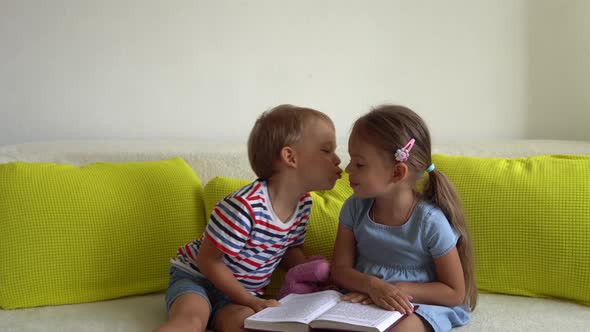 Two Smiling Preschool Toddler Children Read Interesting Book of Fairy Tale On Couch alt
