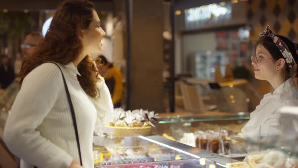 Woman Walking to Cake Shop and Discussing Sweets with Saleswoman alt