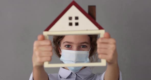 Businesswoman holding model of house with medical mask in hands
