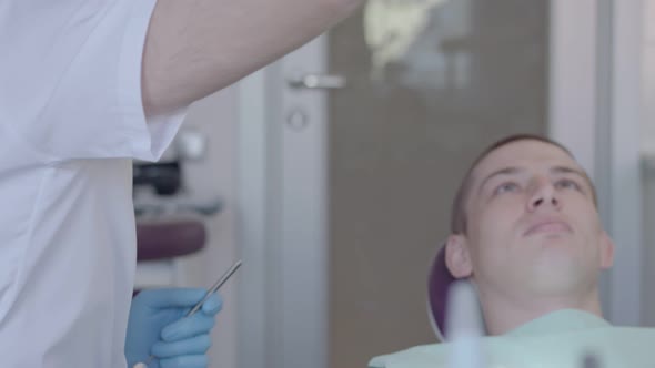 Dentist examines oral cavity of patient.