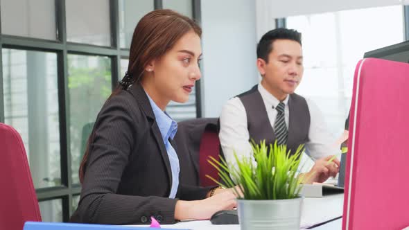 Asian happy young business woman and man typing on keyboard working together as team in office. alt