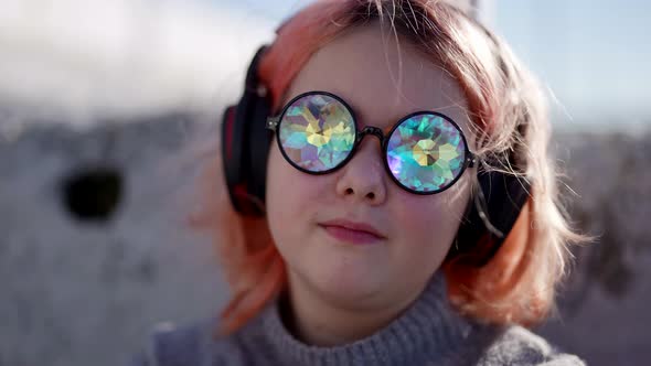 Preteen Girl is Enjoying Music By Headphones on Street Portrait of Child with Funny Glasses alt