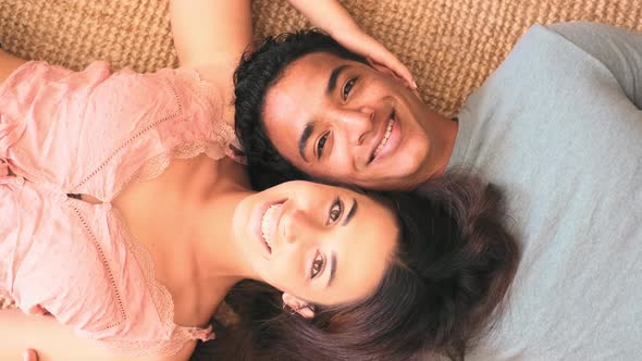 Happy young interracial couple viewed from above laying on the floor at home - cheerful alt