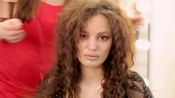 Beautiful Girl with Curly Hair Makes Her Hair in a Beauty Salon