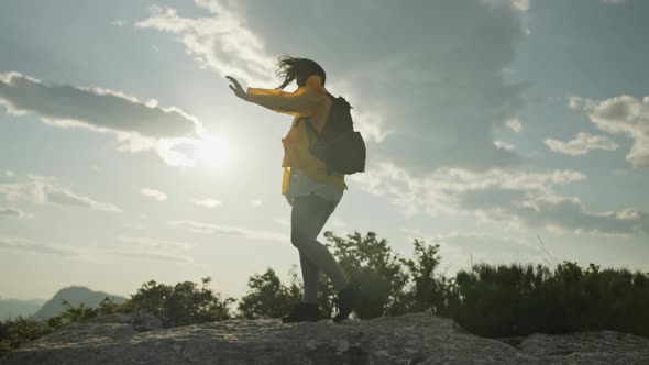 The Girl is Hiking Along the Rocks of the Mountain Range alt